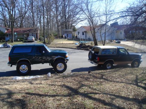 1995 Ford Bronco - Two Ford Broncos are parked on a residential street on a sunny day.