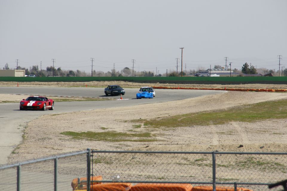 Red and white sports car, blue car, and dark sedan on a race track