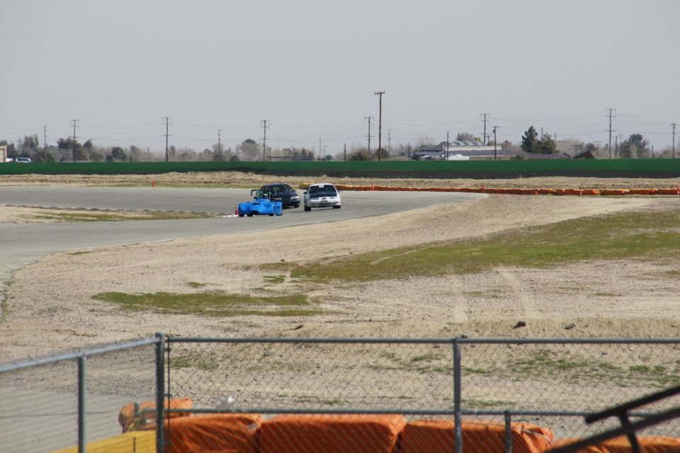 Blue race car and white sedan on a race track
