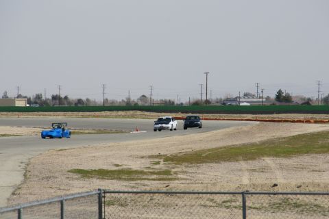 1995 Ford Taurus - Multiple vehicles are seen on a race track under a hazy sky.
