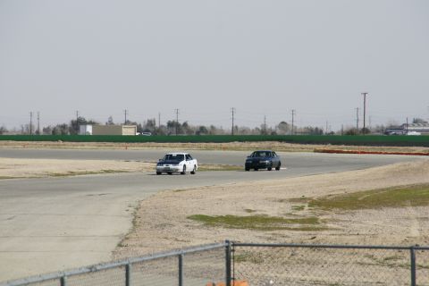 1995 Ford Taurus - Two cars are seen on a racetrack during a sunny day.