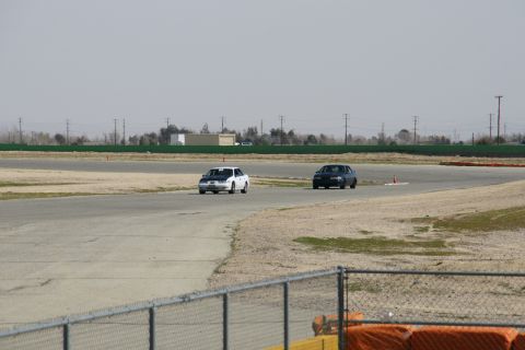 1995 Ford Taurus - Two cars compete on a race track under a hazy sky.