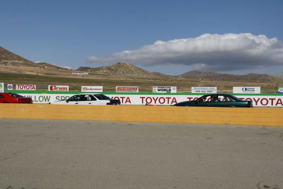 Cars lined up on a racetrack with mountains in the background