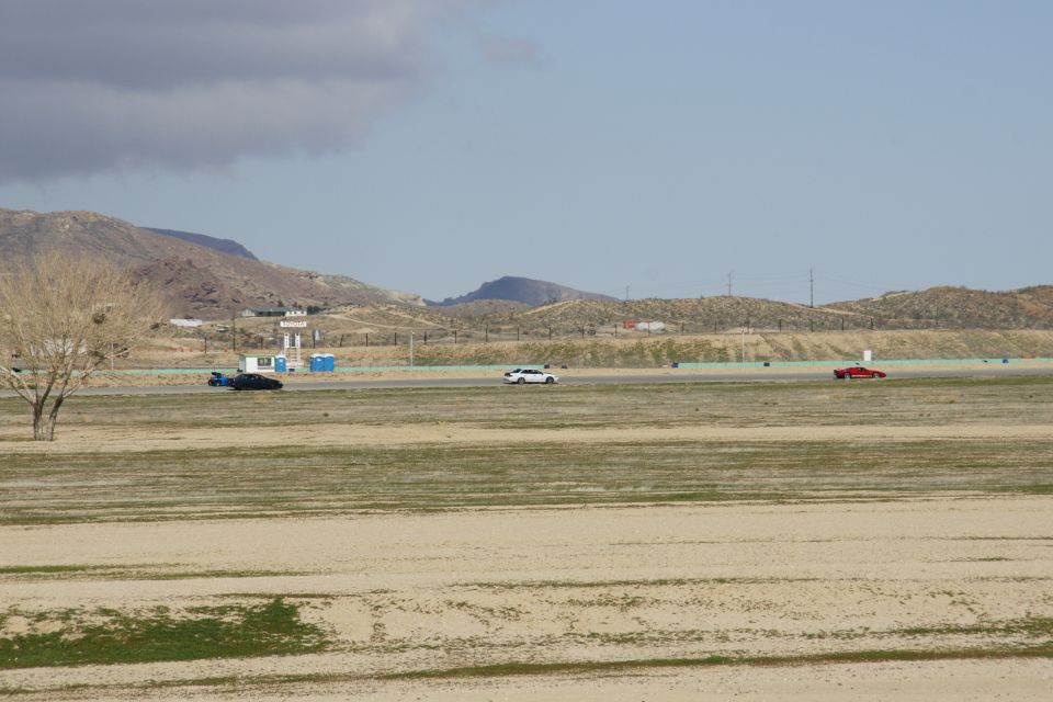 Three cars on a racetrack with mountains in the background