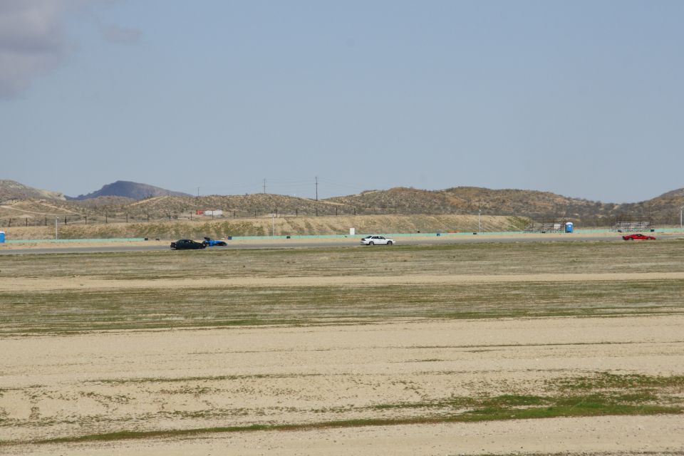 Cars on a race track with hills in the background