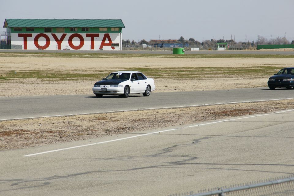 White sedan with black hood on race track, number 69 on windshield