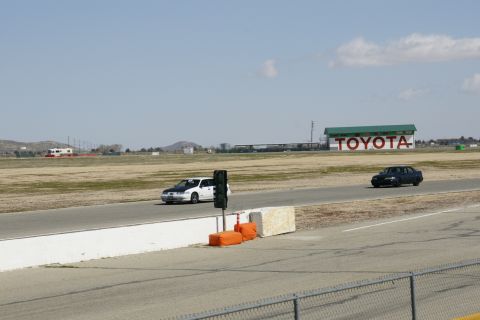 1995 Ford Taurus - Two sedans on a racetrack with a Toyota building in the background.