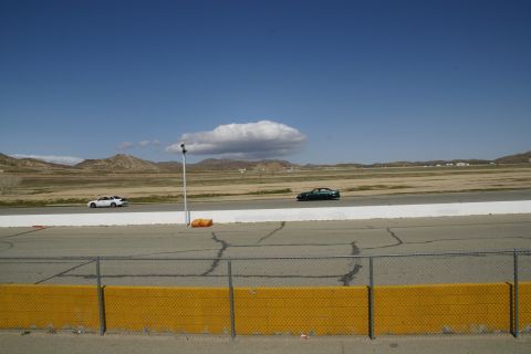 1995 Ford Taurus - Two sedans on a racetrack with dry hills in the background.