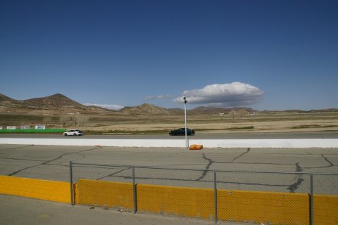 1995 Ford Taurus - A wide shot of a race track with two cars visible under a bright blue sky.