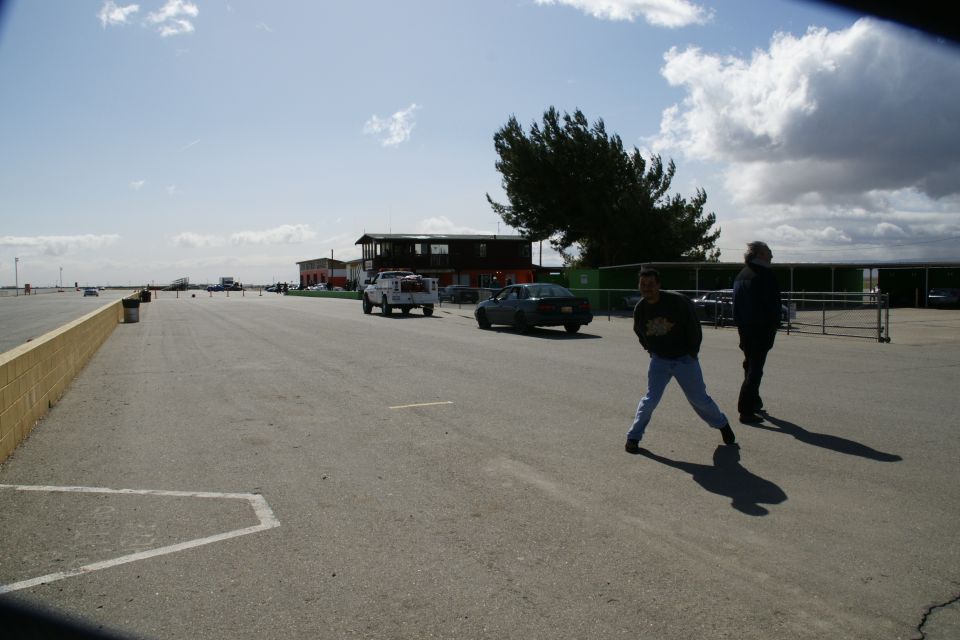 People walking across an open paved lot at a racetrack or airfield