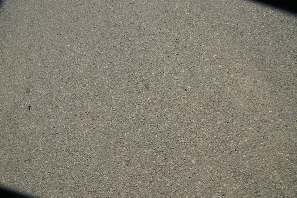 Asphalt road surface with small pebbles and a shadow in the upper right corner