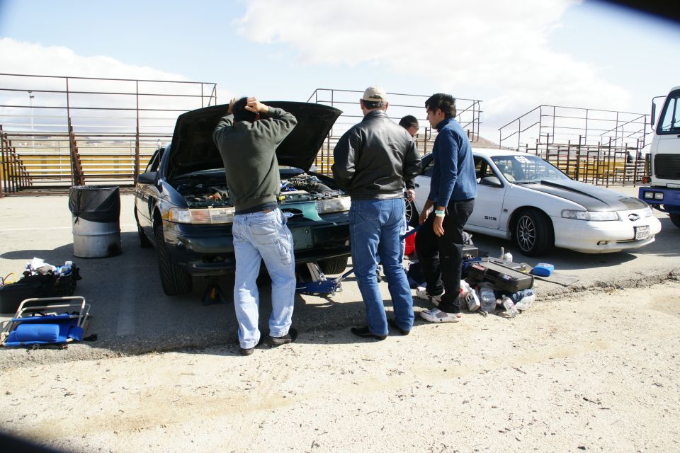 1995 Ford Taurus with hood open, people gathered around, white car in background