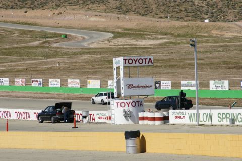 1995 Ford Taurus - A view of the Willow Springs International Raceway with several vehicles present on the track and pit area.