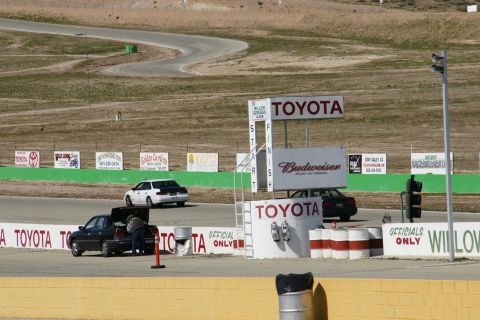 1995 Ford Taurus - Multiple vehicles are present on a race track, including a pickup truck with its trunk open and two sedans.
