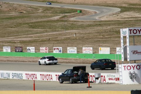 1995 Ford Taurus - Cars on a race track at Willow Springs, with various sponsor signs visible along the course.