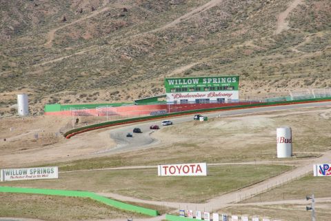 1995 Ford Taurus - A view of the Willow Springs race track with several cars on the course and prominent sponsor signage.