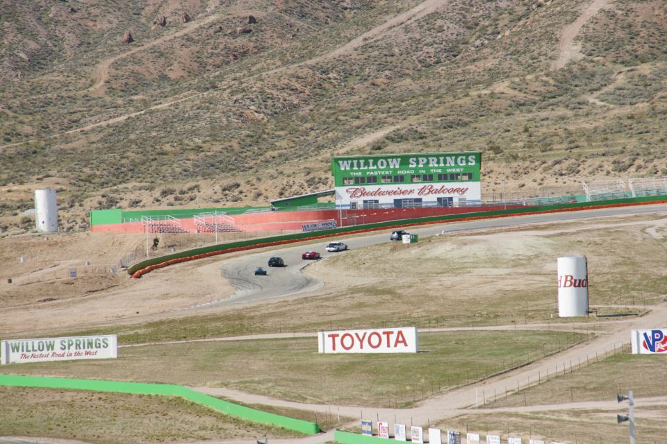 Cars on a race track with Willow Springs signage and Budweiser Balcony grandstands