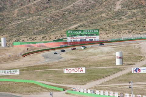 1995 Ford Taurus - Cars race on the track at Willow Springs, with the Budweiser Balcony grandstand in the background.