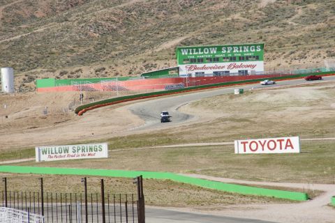 1995 Ford Taurus - A race track scene with multiple vehicles visible on the asphalt and surrounding buildings.