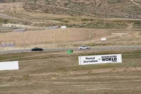 1995 Ford Taurus - Two cars are seen on a racetrack with a sign in the foreground that advertises road racing.