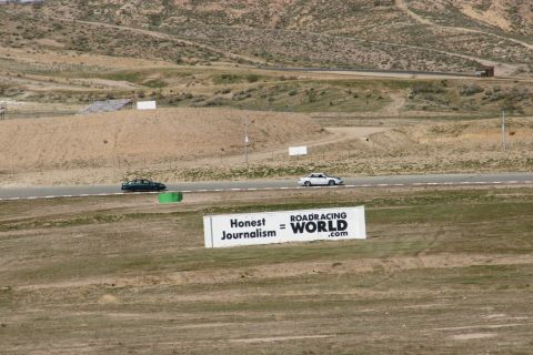 1995 Ford Taurus - Two sedans are seen on a racetrack, with a large sign in the foreground reading "Honest Journalism = ROADRACING WORLD.com".