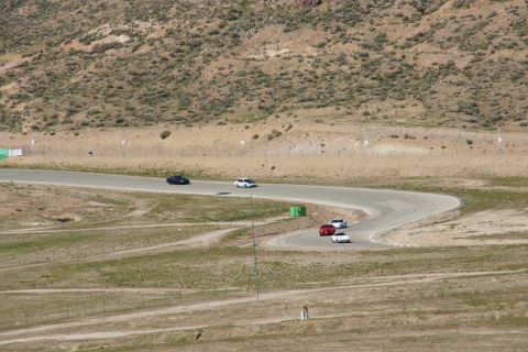 1995 Ford Taurus - Cars navigate a turn on a race track surrounded by arid hills.