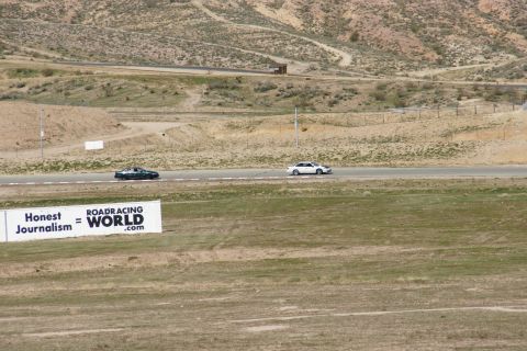 1995 Ford Taurus - Two cars compete on a race track, with a prominent sign for ROADRACING WORLD visible in the foreground.