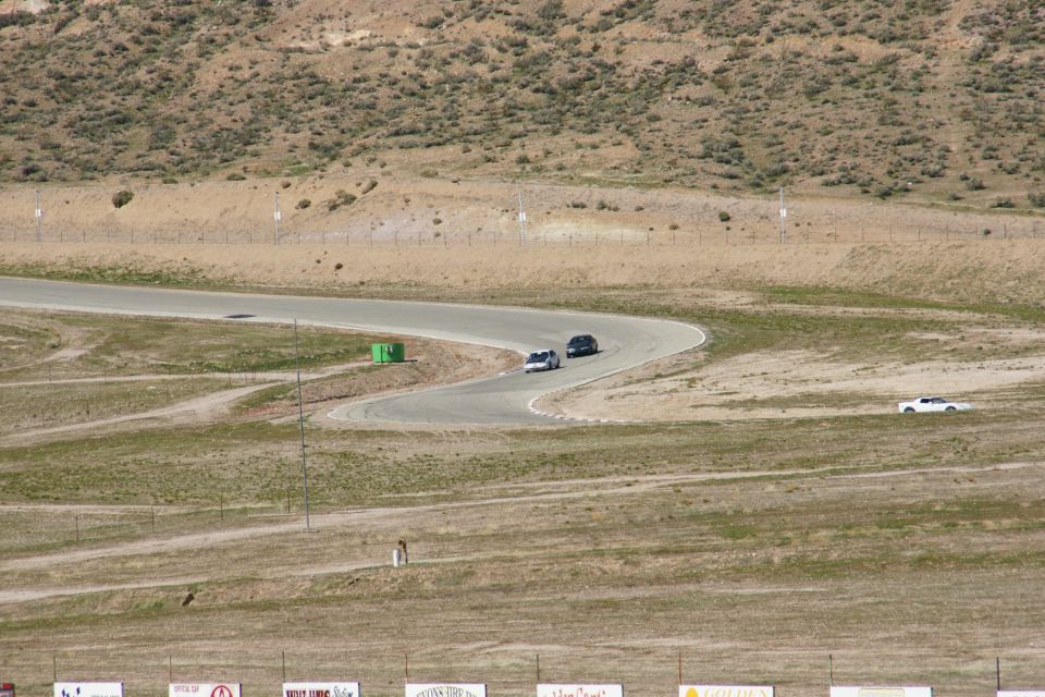 Cars driving on a winding race track with dry hills in the background