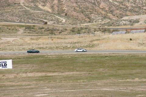 1995 Ford Taurus - Two sedans race on a track surrounded by arid hills, with a sign for Racing World visible.
