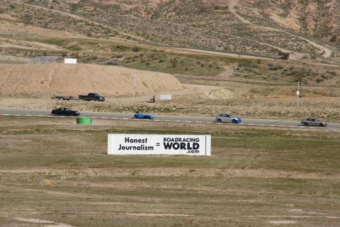 1995 Ford Taurus - Several cars are seen racing on a track with a large sign in the foreground.