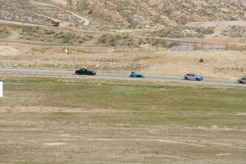 1995 Ford Taurus - Cars on a racetrack with dry, hilly terrain in the background.