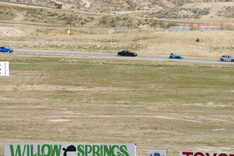 1995 Ford Taurus - Several cars are seen on a race track at Willow Springs, with spectators in the foreground.