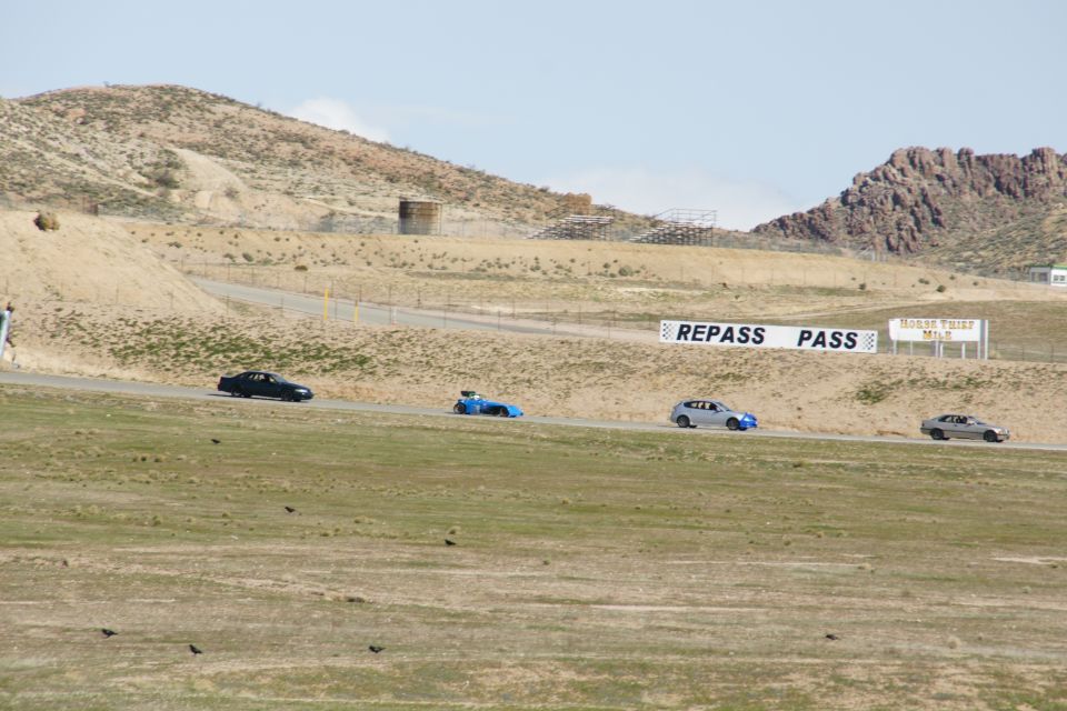 Four cars race on a track with 'REPASS PASS' sign