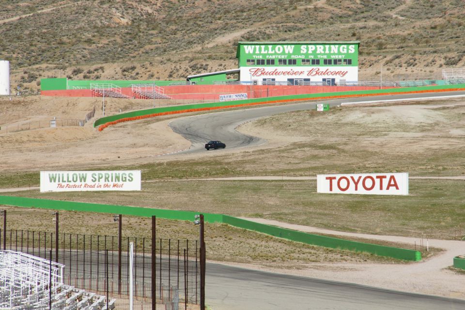 Willow Springs International Raceway with a dark sedan on the track and Toyota signage