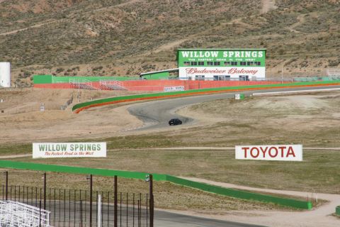 1995 Ford Taurus - A black sedan navigates a turn at Willow Springs International Raceway, with prominent signage visible.