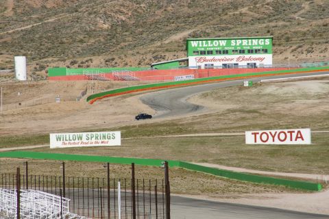 1995 Ford Taurus - A black sedan navigates a turn at Willow Springs International Raceway, with prominent signage for Willow Springs and Toyota visible.