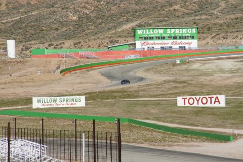 1995 Ford Taurus - A car navigates a turn on the Willow Springs International Raceway, with signage for Willow Springs and Toyota in the background.