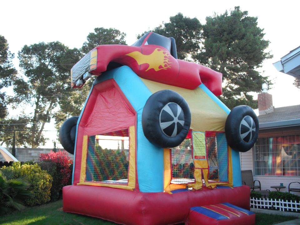 Inflatable bounce house with red race car top and large black wheels