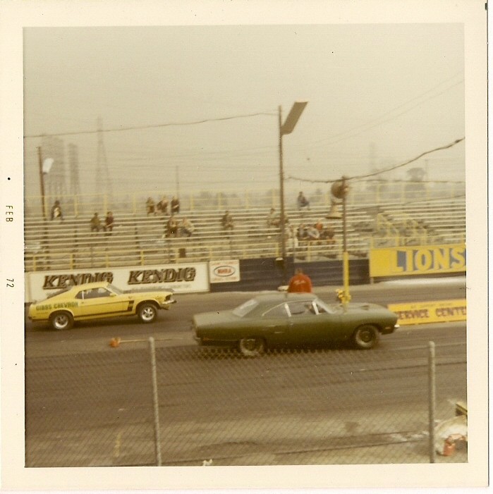 Green muscle car racing on a track, side view. 1970 model