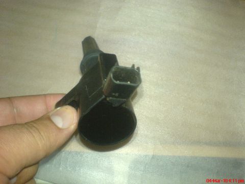 1998 Ford Crown Victoria - A black ignition coil with a plastic electrical connector is held for inspection.