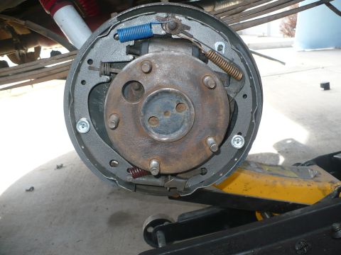 1979 Ford Bronco - Rear drum brake assembly with the drum removed, showing new gray shoes, a blue return spring, gold and red springs, self-adjuster hardware…