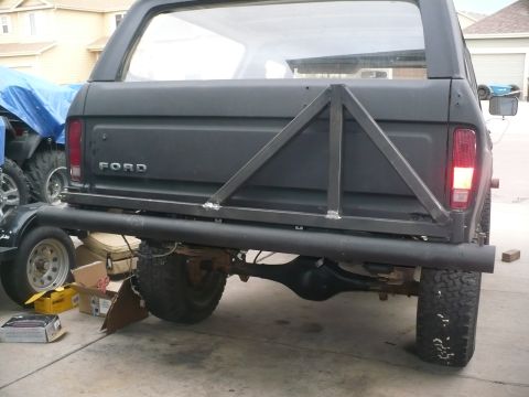 1979 Ford Bronco - Rear view of a flat-black lifted Ford SUV in a driveway with a shop-built tube rear bumper and welded triangulated square-tube tailgate bra…