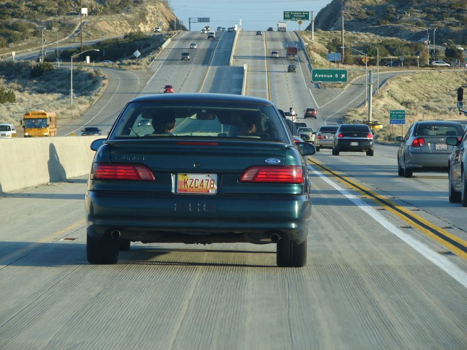 Rear view of a 1992 Ford Taurus driving on a highway. License plate KZC478