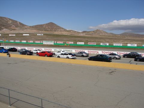 1992 Ford Taurus - Multiple vehicles are parked on a race track with sponsor banners visible in the background.