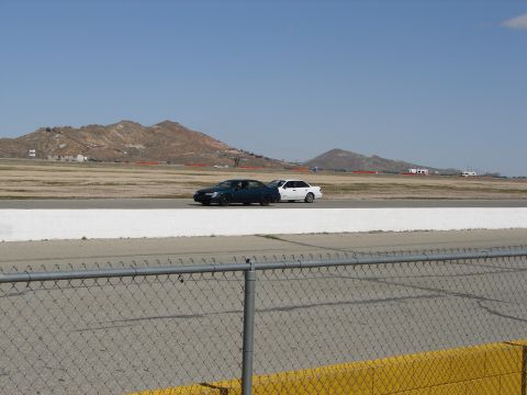 1992 Ford Taurus - Two sedans are seen on a racetrack with mountains in the background.