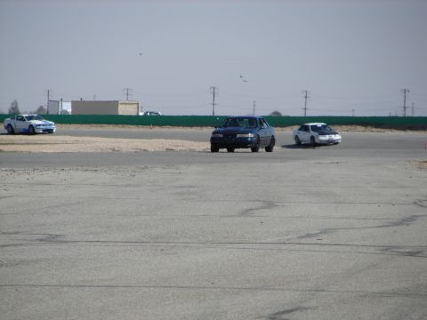 1992 Ford Taurus - Multiple vehicles are seen on a paved track under a hazy sky.