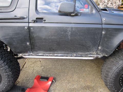 1996 Ford Bronco - This Ford Bronco features custom rock sliders and aggressive off-road tires, suggesting it's modified for terrain.
