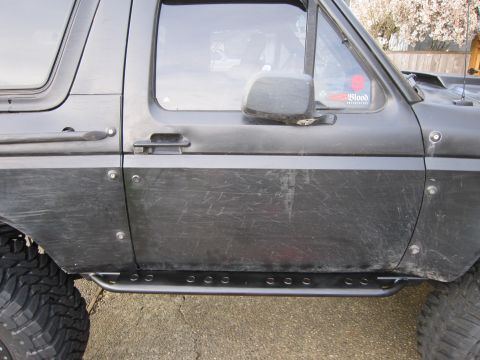1996 Ford Bronco - Side view of a black 1996 Ford Bronco, rock sliders and off-road tires.