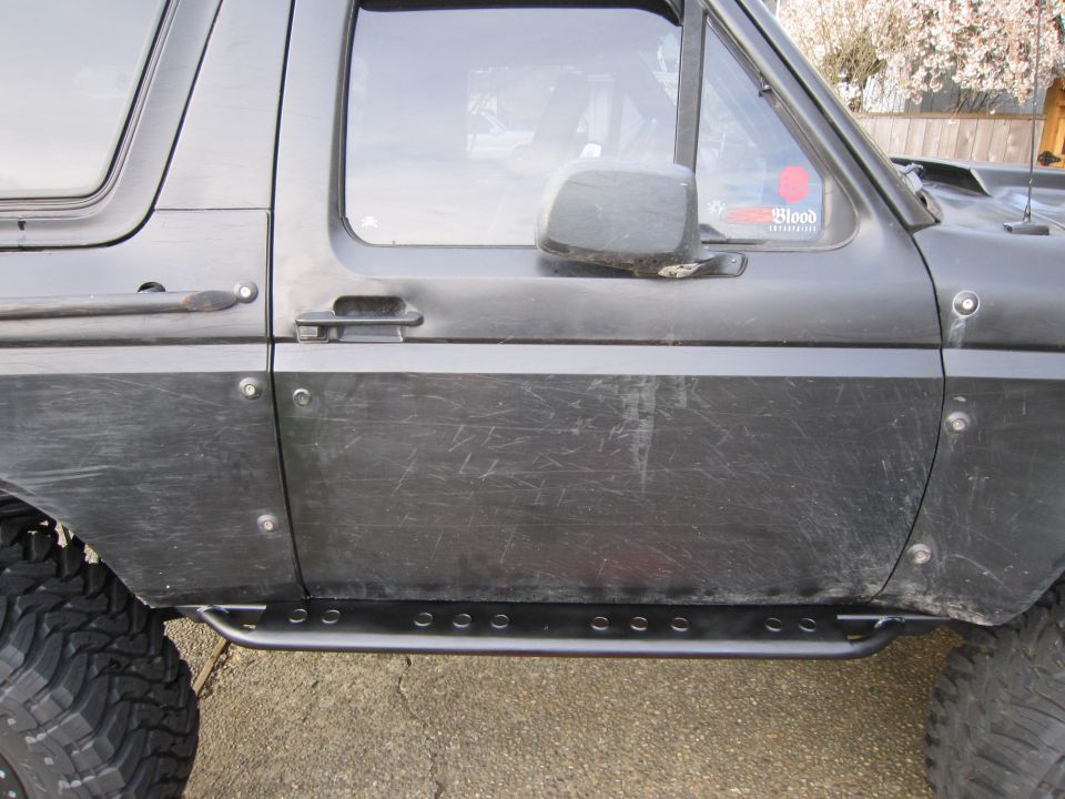 Black 1996 Ford Bronco side door with rock sliders and off-road tires