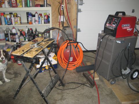 1996 Ford Bronco - Garage scene with welding equipment, a workbench, and a dog. A white garage door is in the background.